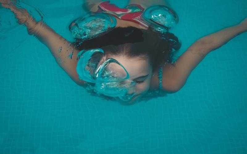 a woman wearing goggles and swimming underwater