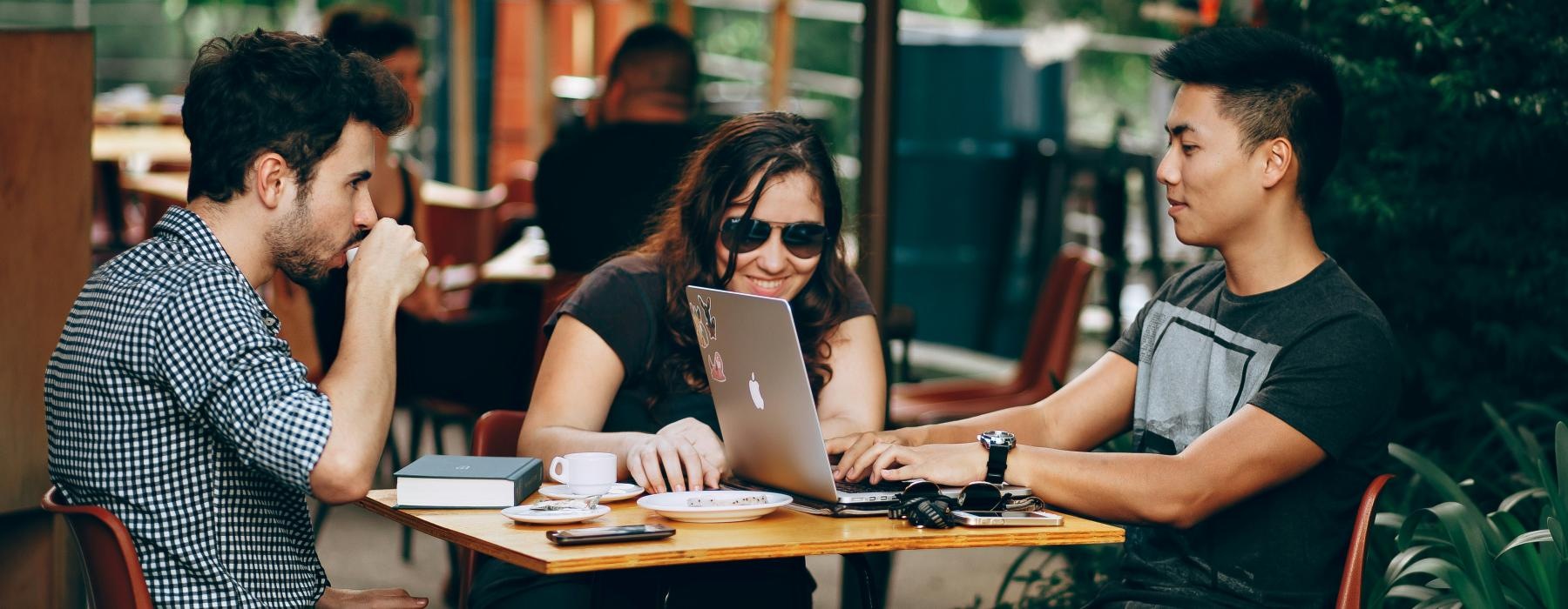 a group of people sitting around a table with a laptop