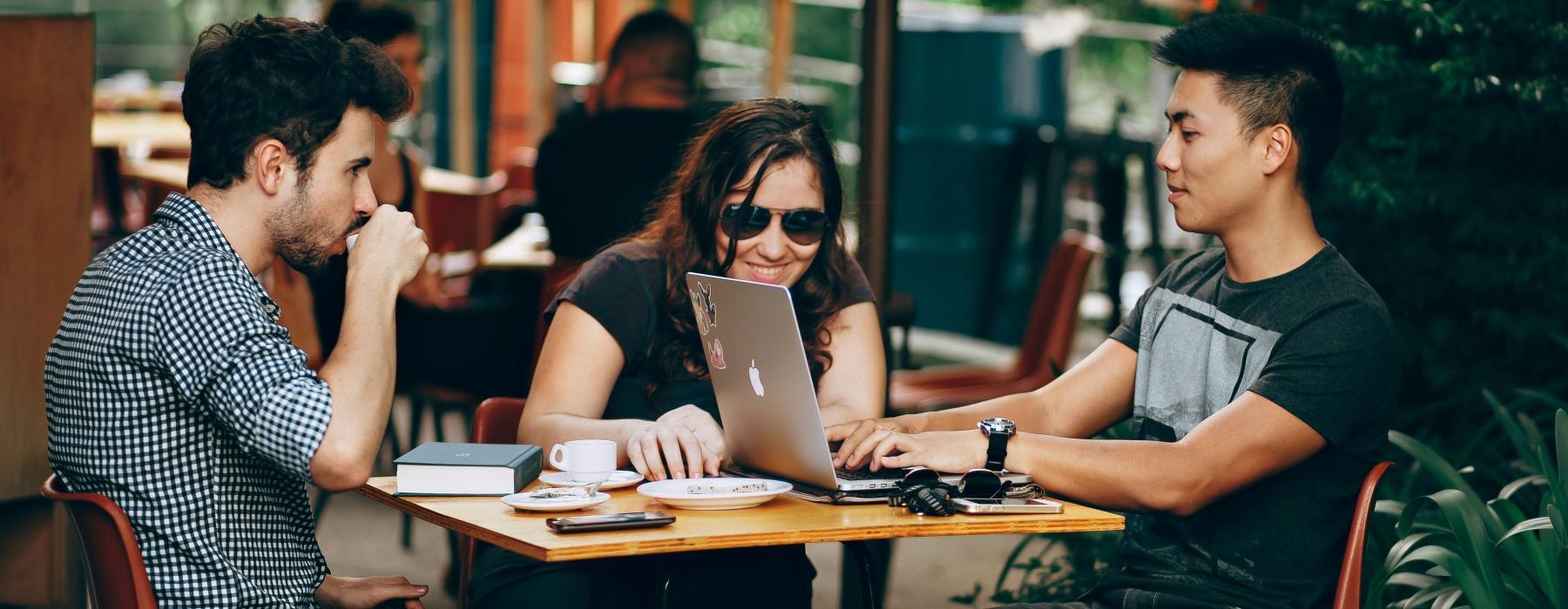 a group of people sitting around a table with a laptop